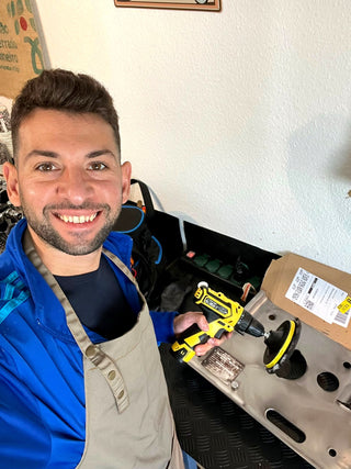 Antonino mit Schürze und Akkuschrauber in der Werkstatt (Selfie)