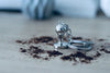 Barista-Tamper-Schlüsselanhänger mit Schlüsselring, seitlich auf Holztisch mit Kaffeepulver