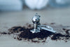 Barista-Tamper-Schlüsselanhänger in Silber auf Kaffeepulver