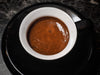 Miscela Extra Bar als Espresso mit Crema in weißer Tasse auf schwarzer Untertasse, Draufsicht