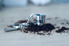 Silberner Milchkannen-Schlüsselanhänger, Nahaufnahme mit verstreutem Kaffeemehl