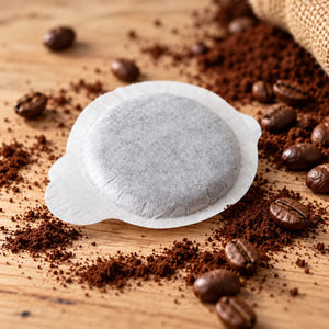 Celano E.S.E. Kaffeepad aus Filterpapier auf Holztisch mit gemahlenem Kaffee, Kaffeebohnen und Jutesack