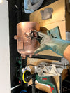 Kupferkessel wird in der Werkstatt aufbereitet (Draufsicht, Handschuh, Poliermaschine)